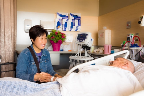 caregiver holding an elderly man's hand