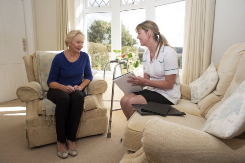 caregiver on a home visit talking with an elderly female patient