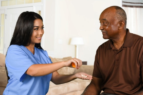 caregiver helping an elderly patient take his pills